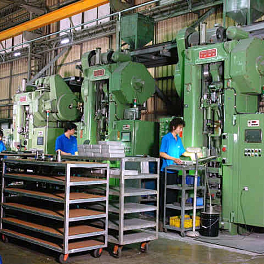 Operators at compacting presses with trays of sintered parts